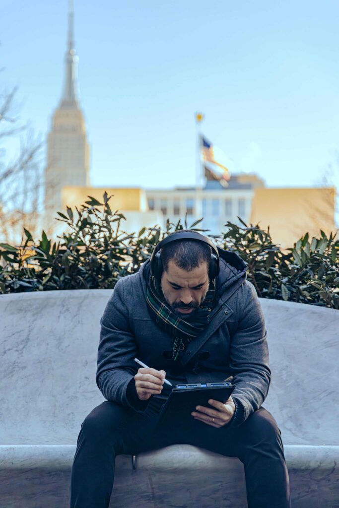 Victor Maia Mignone sentado no Hudson Yards trabalhando ao fundo Empire States Building